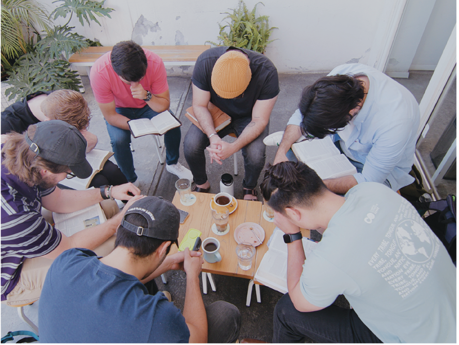 Group of men praying in a circle.